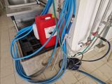 un conteneur rouge muni de tuyaux bleus, à côté d'un conteneur rouge contenant une bidon rouge