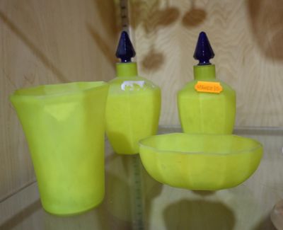 trois vases jaunes et un bol posés sur une étagère en verre