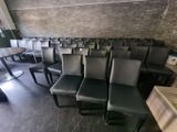 rows of black chairs in a room with a brick wall behind them