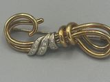 une photo en gros plan d'une broche en forme de nœud, en or et diamants