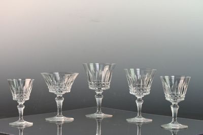 six wine glasses sitting on a glass shelf on a table