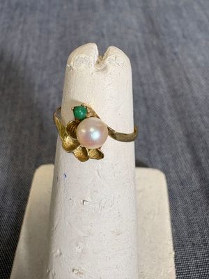 une bague ornée d'une perle et d'une pierre verte