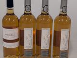quatre bouteilles de vin sont alignées sur une surface blanche