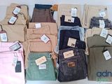 de nombreux pantalons de différentes couleurs posés sur une table, avec leurs étiquettes de prix