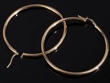 pair of gold hoop earrings on a black surface