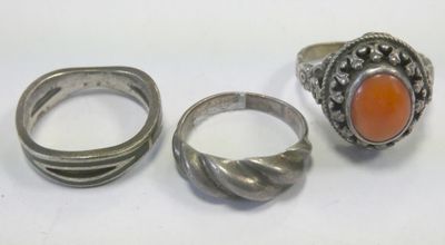 three silver rings and a ring with an orange stone