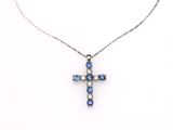 un pendentif en forme de croix, orné de diamants bleus et blancs, monté sur une chaîne en argent