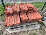 un tas de briques posé sur une palette devant une clôture