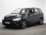La BMW Tourer noire est garée dans une pièce au sol carrelé.