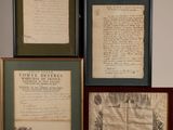 trois documents encadrés sont posés sur une étagère à côté d'une chaise en bois