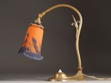 an orange and blue lamp with a gold base on a white table