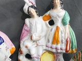 three ceramic figurines of people sitting on top of a table