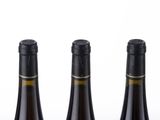 six bottles of wine are lined up in a row on a white surface