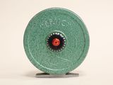 a green metal object with a red button on it