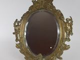 un miroir ancien avec un cadre doré posé sur un support blanc