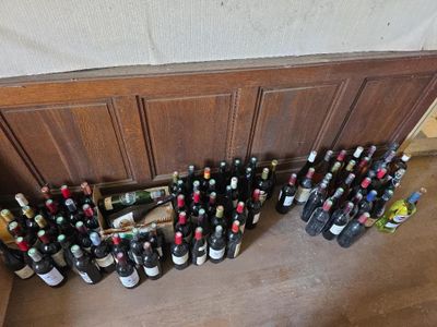 de nombreuses bouteilles de vin posées par terre près d'un mur