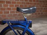 a blue bicycle with a black seat in front of a brick wall