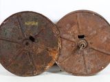 two old rusty reels sitting on top of a white surface