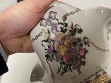 a hand that is holding a tea pot on a table