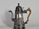 une cafetière en argent avec une poignée en bois sur une surface blanche