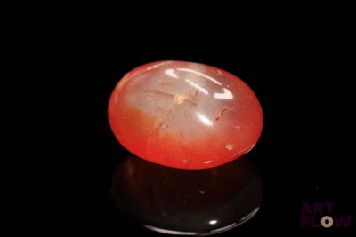 a close up of a red and white stone on a black surface