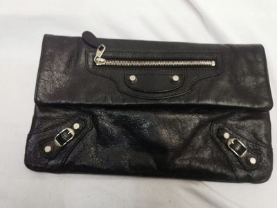 un gros plan d'un sac à main en cuir noir posé sur une surface blanche