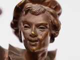 bronze statue of a woman holding a glass of wine in her hand
