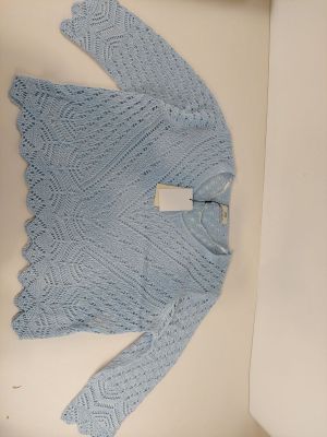 un pull bleu en tricot dans une boîte posée par terre