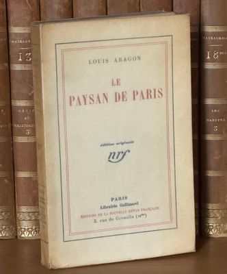 un livre posé sur une étagère, devant une pile de livres