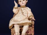 une poupée ancienne assise sur une chaise, vêtue d'une robe dorée