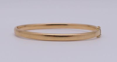 un gros plan d'un bracelet rigide en or sur fond blanc