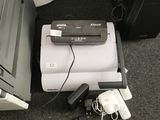 une photo montrant une imprimante et d'autres appareils électroniques posés par terre