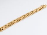 a close up of a gold chain bracelet on a white surface