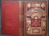 an old book with a red cover sitting on top of a table