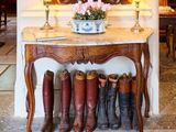 une table sur laquelle sont posées plusieurs paires de bottes, devant un miroir