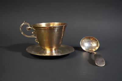 a silver cup and a spoon on a black table