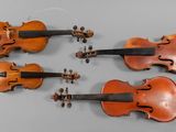 four antique violin ' s on a gray surface