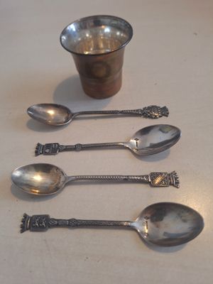 quatre cuillères et une tasse posées sur une table, avec une tasse en arrière-plan