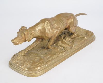 statue en bronze représentant un chien, posée sur un plateau, sur une surface blanche