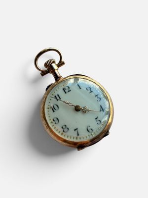 une montre de poche en or avec un cadran blanc sur une surface blanche