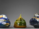 three different colored vases sitting side by side on a gray surface