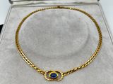 a gold bracelet with a blue stone on it in a box