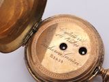 a close up of a gold pocket watch on a white surface