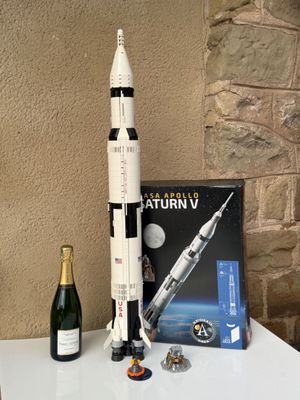 une maquette de la fusée Saturn V et une bouteille de champagne posées sur une table