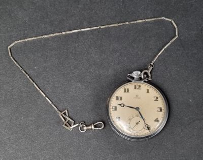 a silver pocket watch on a chain on a black surface