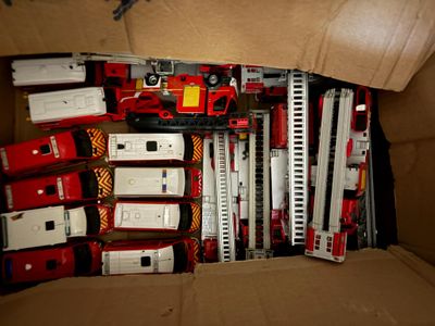 a cardboard box filled with toy fire trucks and ladders