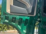 a green truck with the door open and the driver ' s seat down