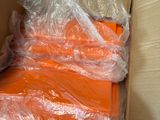 plusieurs sacs remplis de t-shirts orange, posés dans une boîte par terre