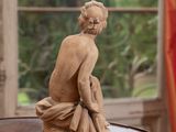 a statue of a woman sitting on a table in front of a window