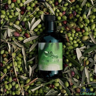 une bouteille d'huile d'olive posée sur une pile d'olives